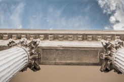 Stock image of pillars looking upward toward a blue sky.